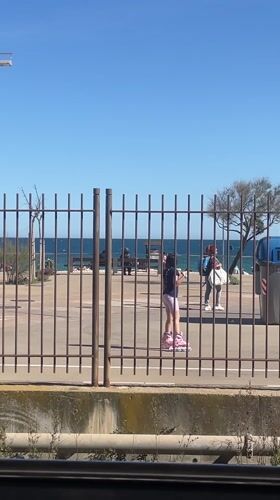 Girl roller skates along fence in Badalona, Spain