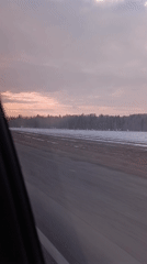 Car travels wet road through snowy Russian countryside