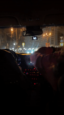 Nighttime car ride captured in Klin, passenger waves