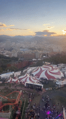 Bilbao fairground at dusk, roller coaster and Ferris wheel under stormy skies