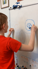 Child creates colorful artwork on whiteboard with markers