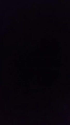 The video is entirely dark. There is a faint light source that appears briefly in the lower right corner. A high-pitched sound that could be a child's voice is audible.