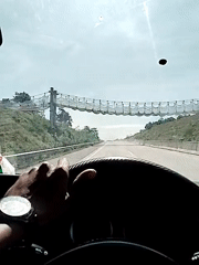 Driver travels highway near suspension bridge in Lamtamot, Indonesia