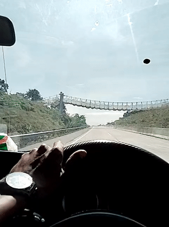 Driver travels highway near suspension bridge in Lamtamot, Indonesia