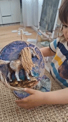 Child displays handcrafted horse artwork in Kempelevo, Russia