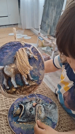 Child displays handcrafted horse artwork in Kempelevo, Russia