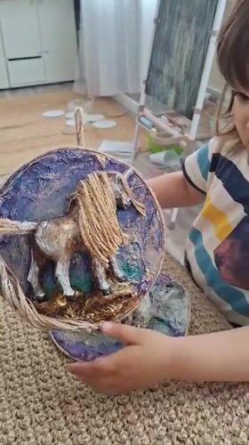 Child displays handcrafted horse artwork in Kempelevo, Russia