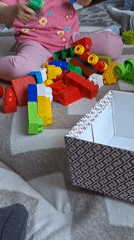 Child plays with building blocks while adult tidies home