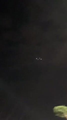 The video captures a dark night sky with a distant object featuring multiple bright lights. The object, which appears to be an aircraft, is seen moving across the frame. Its lights, initially distinct, become less focused as the video progresses or the object moves further away. The sky is dark and featureless, emphasizing the glowing lights. No other details of the surroundings or ground are visible, suggesting the recording is focused solely on the airborne object. The event takes place at night in Mechouar Kasbah, Morocco. No text is visible.