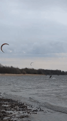 Kiteboarders ride choppy waters near Kronstadt under overcast skies