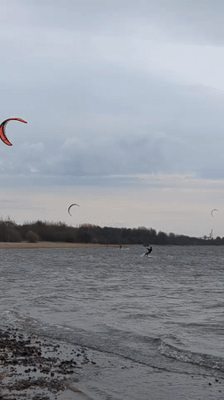 Kiteboarders ride choppy waters near Kronstadt under overcast skies