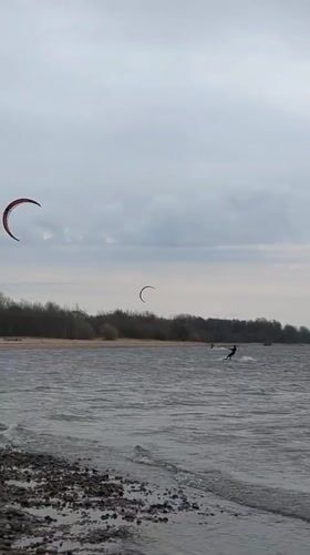 Kiteboarders ride choppy waters near Kronstadt under overcast skies