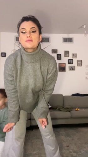 Woman dances in living room while family watches