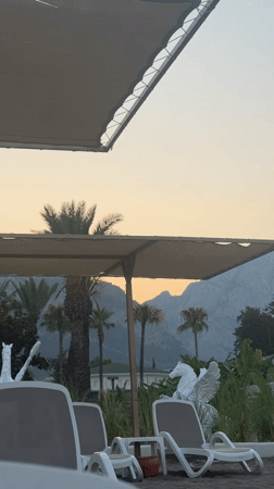Kemer beach resort at golden hour, chairs and mountains.