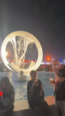Outdoor concert night in Rio, fountain and Ferris wheel nearby.