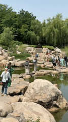 Park visitors cross pond via stepping stones in Yanta District