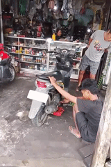 Routine motorcycle maintenance underway at a small Cermo repair shop