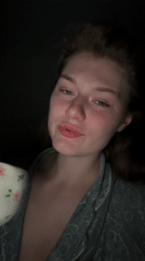 Woman drinks from floral cup in dimly lit Kazan setting