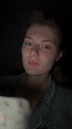 Woman drinks from floral cup in dimly lit Kazan setting
