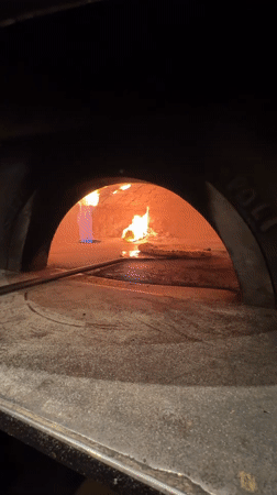 Wood-fired pizza cooking in a stone oven, West Palm Beach