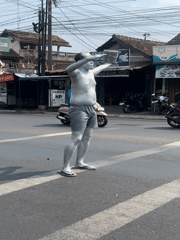 Silver-painted street performer works a pedestrian crossing in Sinduadi