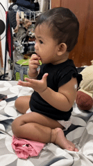 Baby sitting cross-legged on a patterned bed in Malang