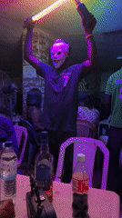 Person in clown mask performs with light bars in Nigeria