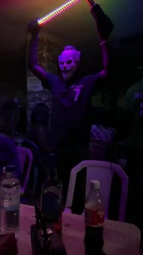Person in clown mask performs with light bars in Nigeria