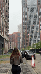 Woman in leather jacket walks between apartment buildings
