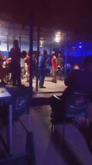 Nighttime bar gathering with stage performance captured by witnesses