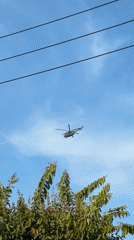 Helicopter passes over Đà Nẵng skyline through power lines