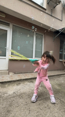 Young girl plays with bubbles in outdoor courtyard