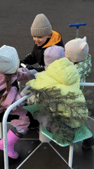 Children play on Moscow playground merry-go-round in winter gear