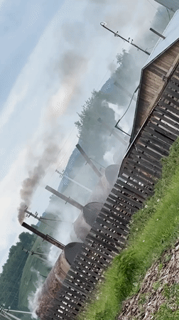Rural Russian village shows industrial smoke amid pastoral scenes