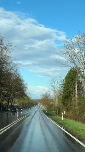 Wet road reflects sky in Junglinster, Luxembourg