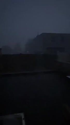 This video captures the phenomenon of lightning striking during a storm. The first frame shows a dark, hazy sky with a faint outline of buildings in the background. A single vertical streak of light, indicative of lightning, appears and quickly dissipates. Subsequent frames show the continuation of the stormy weather with increased visibility of lightning strikes. In the second frame, a brighter, more defined bolt of lightning is visible, illuminating the dark sky and casting shadows on the building structures. The third and fourth frames show the lightning continuing to strike, with multiple flashes and streaks of light illuminating the scene. The video concludes with the final frame depicting the storm in full force, with the sky filled with bright flashes of lightning.