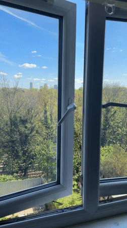 Window opened revealing London green space and skyline view