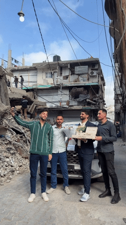Young men pose with flowers near damaged Gaza building