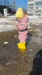 Toddler plays in puddle during sunny spring day