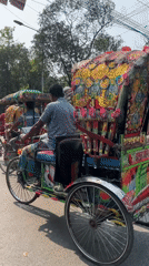 Ornate rickshaws navigate sunny Dhaka streets during morning commute
