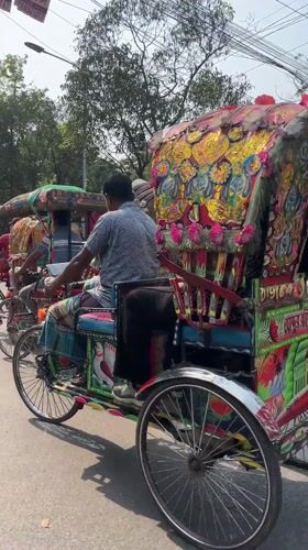 Ornate rickshaws navigate sunny Dhaka streets during morning commute