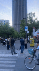 Street performer sings on Paris cobblestone sidewalk at dusk