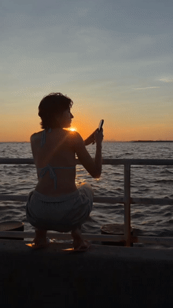 Perched on a ledge at sunset, NYC skyline across the water