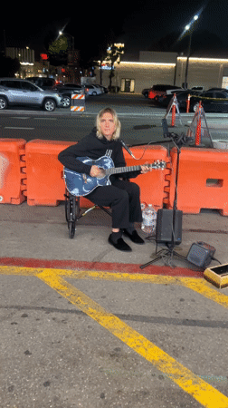 Wheelchair musician performs on LA street near neon-lit storefronts