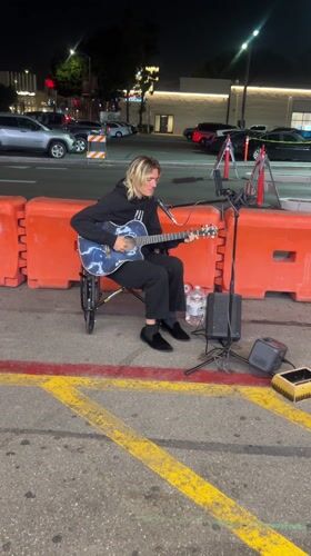 Wheelchair musician performs on LA street near neon-lit storefronts