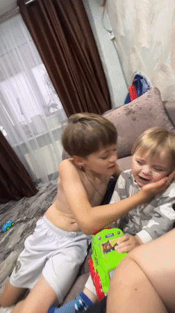 Two boys share affectionate moment on couch in Noviy