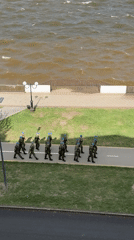Military unit marches near Votkinsk embankment amid rough waters
