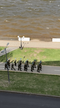 Military unit marches near Votkinsk embankment amid rough waters