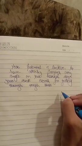 A person's hand holding a blue pen is writing on lined paper. The text on the paper reads: "Your potential is limitless. You have already survived every single on your hardest days. Your track record for getting through tough times is 100%". The paper is in a notebook, and part of the notebook's cover is visible at the top.