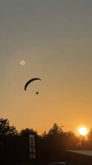 Paraglider soars through shifting sky at golden hour
